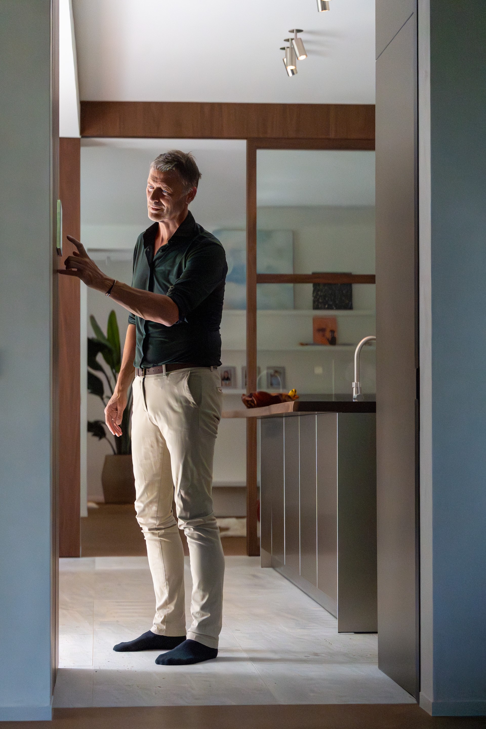 Een man past eenvoudig de temperatuur van zijn woning aan dankzij het centraal gestuurd binnenklimaat.