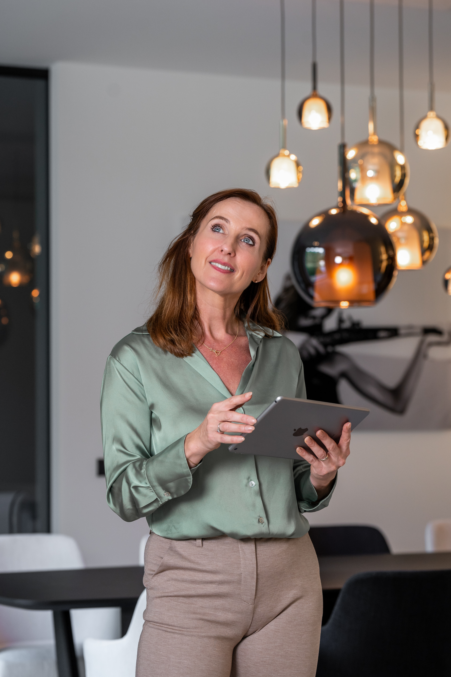 Een vrouw gebruikt een tablet om het domoticasysteem van haar woning aan te sturen.