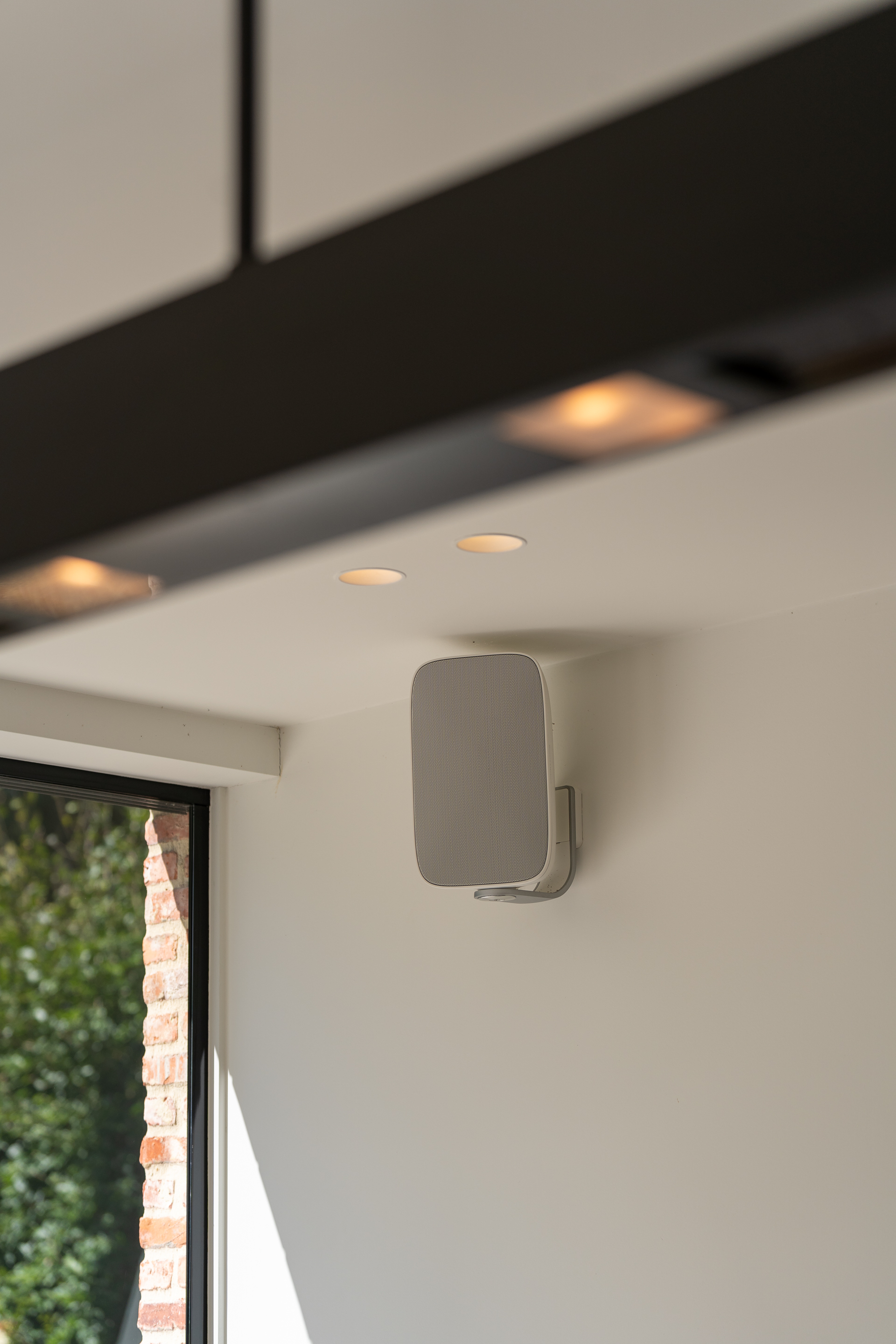 Een speaker hangt aan de muur in een woning en wordt bediend met het centraal gestuurde domoticasysteem.